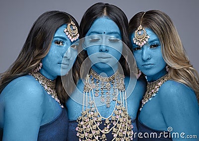 Three South Asian women painted blue and wearing gold jewellery Stock Photo