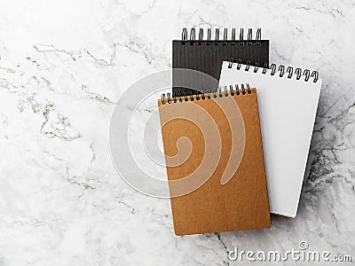 three spiral notebook, black, white and brown, in hard covers on a gray marble background Stock Photo