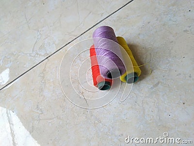 Three spools of colored thread on floor background. Stock Photo