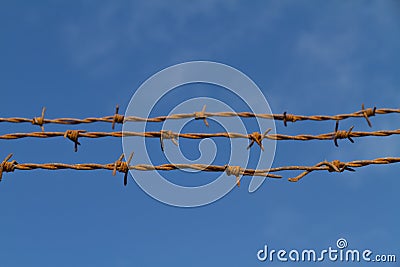 Three strands of rusty barbed wire against the sky Stock Photo