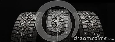 Three studded winter tires wheels in a row on a black background, panoramic shot Stock Photo