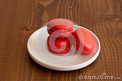 Three Sweet strawberry red macarons on a dark wood background. Tasty colourful macaroons. Stock Photo