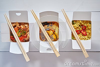 Three take away paper boxes filled with asian food placed in row on white Stock Photo