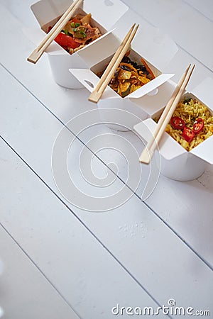 Three take away paper boxes filled with asian food placed in row on white Stock Photo