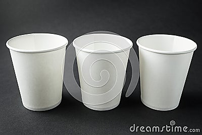 Three take away white paper cups for hot coffee, tea, juice and other beverages isolated on black. Retail mockup presentation Stock Photo