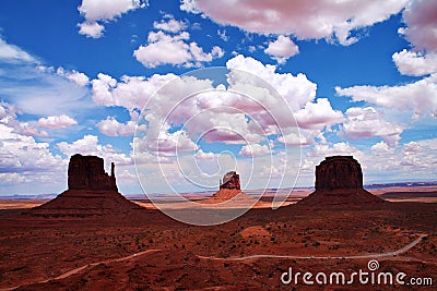 Butte rock formations with dirt road, shadows and fluffy clouds in Monument Valley, Arizona Stock Photo