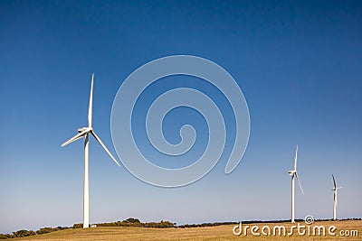 Three tall wind turbines under blue sky. Stock Photo