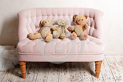 Three teddy bears sitting on pink sofa. Stock Photo
