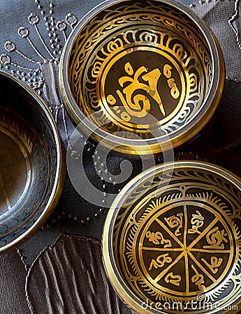 Three tibetan singing bowl on top of a wooden table Stock Photo