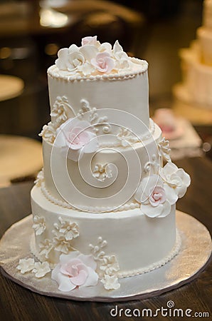 Three tier wedding cake with cream roses and decorations Stock Photo