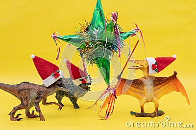 Three toy dinosaurs with Santa Claus hats and a mexican pinata Stock Photo