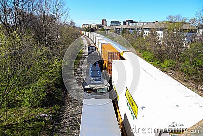 Three trains riding on the railroad tracks surrounded by lush green trees and bare winter trees and clear blue sky in Atlanta Editorial Stock Photo