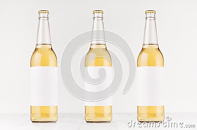 Three transparent longneck beer bottles 500ml with blank white label on white wooden board, mock up. Stock Photo