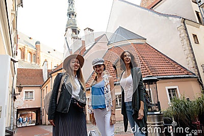 Three traveling girl friends with light backpacks walking exploring Riga city - Travel tourism concept after transfer Stock Photo