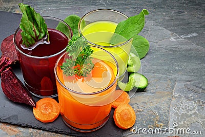 Three types of organic vegetable juice with ingredients on slate Stock Photo