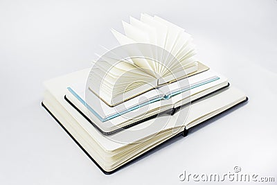 Three unfold notebooks lie on top of each other and fan open notepad with blank light beige pages. Pyramid of books Stock Photo