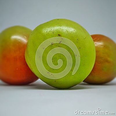 three unripe but fresh looking tomatoes on a white background Stock Photo