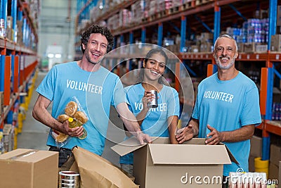 Three volunteers packing eatables in cardboard box Stock Photo