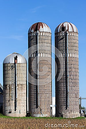 Three weathered silos against blue sky in rural United States Stock Photo