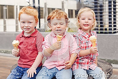 Three white Caucasian cute adorable funny children toddlers sitting together sharing ice-cream Stock Photo