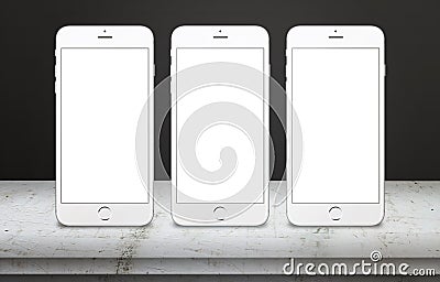 Three white mobile phones on table with blank, white, isolated display screen for mockup Stock Photo