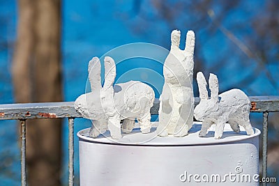 Three white rabbit statues made of plaster on barrel at outdoor art exhibition, artificial hares Editorial Stock Photo