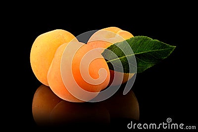 Three whole apricots with leaf isolated on black Stock Photo