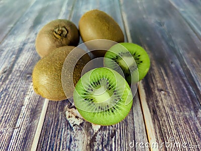 Three whole kiwi fruit and two half. Tropical green fruit on a wooden table. Close up Stock Photo
