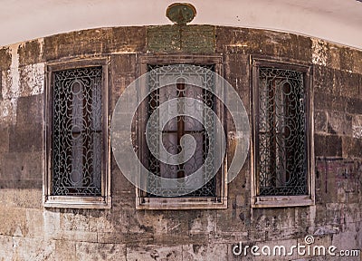 Three windows with ornamented metal lattice on a stone building Stock Photo