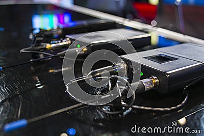 Three wireless microphone transmitter and three wireless microphone reciever on black table in tv studio Stock Photo