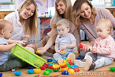 Three woman friends with toddlers playing on the floor in sitting room Stock Photo