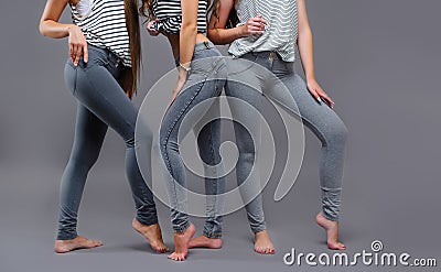 Three women in good form of pop in the legends of Push-Up on a gray background, fashionable advertising advertising space for text Stock Photo