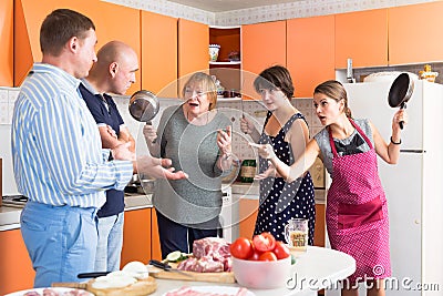 Women opposing men in kitchen Stock Photo