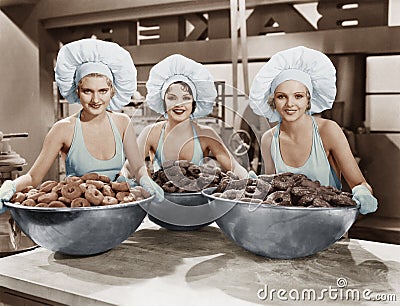 Three women with huge bowls of donuts Stock Photo
