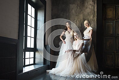 Three women near window wearing wedding dresses Stock Photo