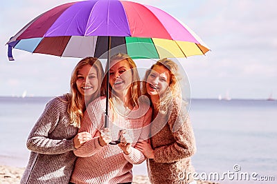 Three women under colorful umbrella Stock Photo