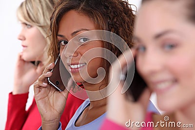 Three women using mobile telephones Stock Photo