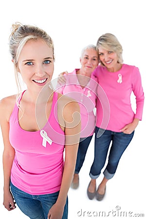 Three women wearing pink tops and breast cancer ribbons Stock Photo