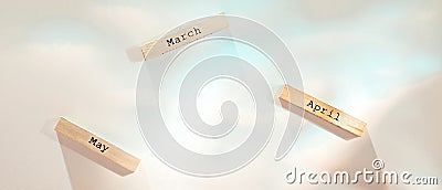 Three wooden blocks with names of spring months on white texture flooded with colorful light Stock Photo