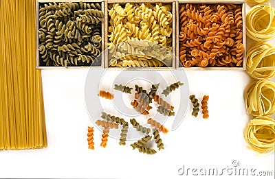 Three wooden boxes with colored fusilli are on a white background next to spaghetti and tagliatelle Stock Photo