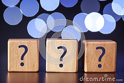 Three wooden cubes with question marks of white circlesa bokeh Stock Photo