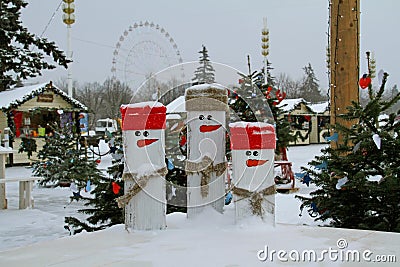 Three wooden snowmen in snow on the background of `Christmas light` festival in VDNKh in Moscow Editorial Stock Photo