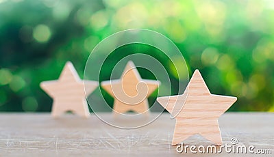Three wooden stars on a green bokeh background. The concept of the rating of hotels and restaurants, the evaluation of critics and Stock Photo