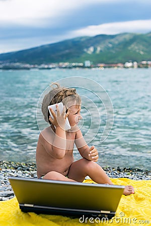 Three year business kid with laptop and smart phone on beach near sea Stock Photo