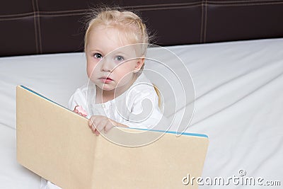 Three year old girl reading a book Stock Photo