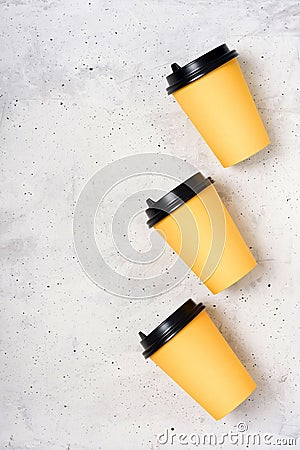 Three yellow paper cups on a light grey concrete background. Flatlay. Place for text on the left. Copy space. Minimalism concept. Stock Photo