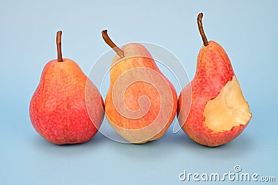 Three yellow-red pears are lined up side by side. One pear has been bitten off a large piece Stock Photo