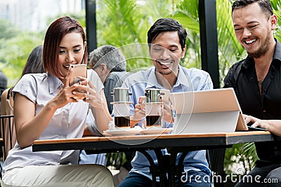 Friends using devices connected to the wireless internet of a modern coffee shop Stock Photo