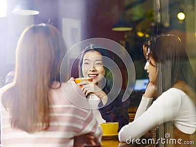 Three young asian women chatting talking in coffee shop Stock Photo