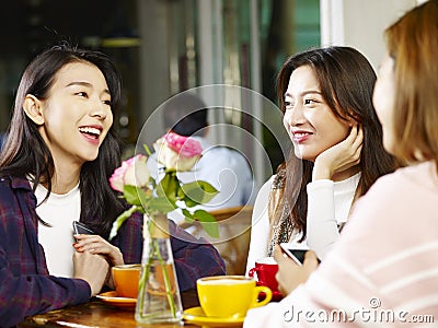 Three young asian women chatting talking in coffee shop Stock Photo